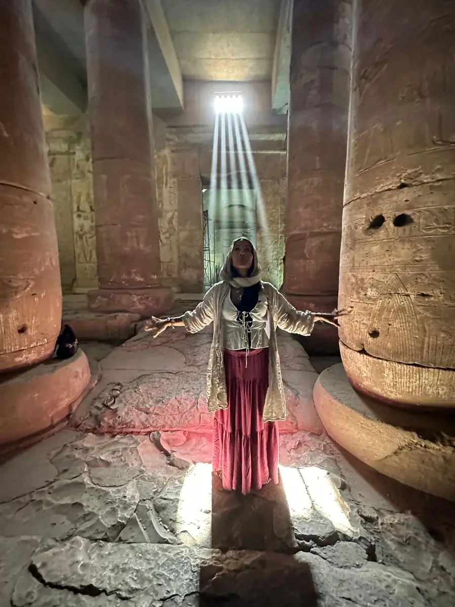 Mulher em meditacao num templo egipcio banhada por um raio de luz